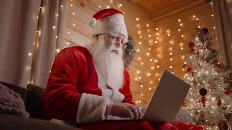Santa Claus is working on the computer at home in the magical Christmas lights Stock Footage 166160076