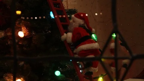 Santa Clause climbing down a ladder from xmas tree 스톡 동영상 83396074