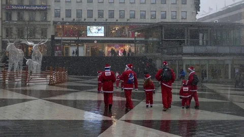 Santa Clauses walking to a statue of Elk the symbol of Christmas Scandinavia Stock Footage 70642300
