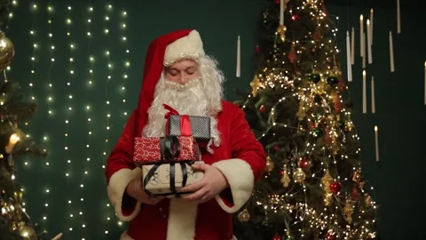 Santa displaying a stack of wrapped Christmas gifts. 動画素材 321517036