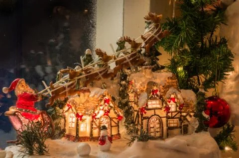 Santa driving his sleigh pulled by reindeer over a lighted house Stock-Fotos