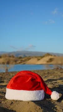 Santa hat resting on sandy beach enjoying warm Christmas holiday Stock Photos