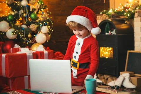 Santa helper using notebook. Child type letter to Santa. Portrait of cute dreamy Foto stock