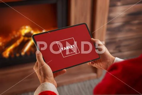 Santa holding tablet near fireplace PSD Template