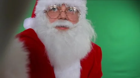 Santa looks at camera on green screen, ideal for holiday messages. Video stock 291544960