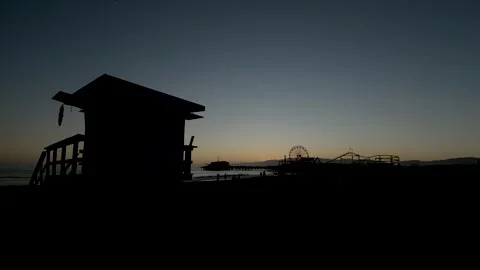 Santa Monica beach after sunset lifeguard tower and Pacific Park in silhouette Stock Footage