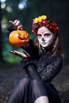 ????? with Santa Muerte make-up sits on a path in forest and holds a Hallow.. Stock Photos