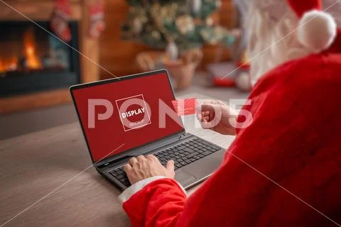 Santa using laptop and card in Christmas cabin PSD Template