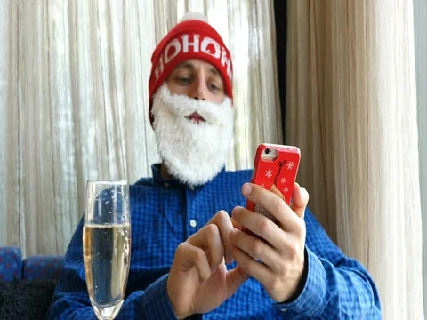 Santa Using Smartphone At Christmas Drinking Champagne At Home Stock Footage 81745126