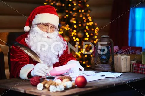 Santa writing letters with quill pen at the table Stock Photos