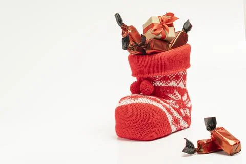 Santa's boot with candy and a small gift on a light background Stock Photos
