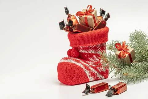 Santa's boot with candy and a small gift on a light background Stock Photos