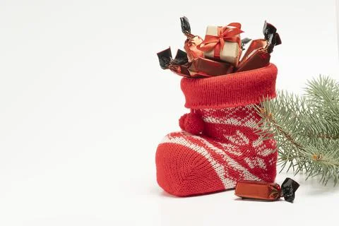 Santa's boot with candy and a small gift on a light background Stock Photos