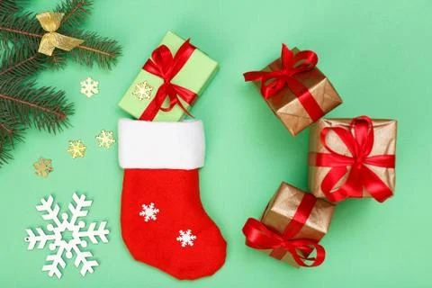 Santa's boot, gift boxes and fir tree branch on green background Stock Photos