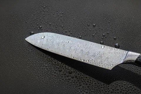 Santoku knife blade with water drops isolated on a black background Stock Photos