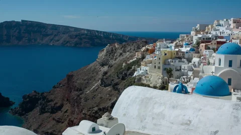 Santorini, Oia Old Town - Slow pan from bell tower, sea to blue domed buildings Stock Footage 34999244