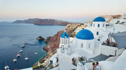 Santorini's beautiful blue-domed churches, caldera, and sea at sunrise Stock Footage 337553253