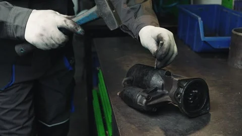 Сar mechanic disassembles an old car starter stained with oil in a workshop Stock Footage 284544097