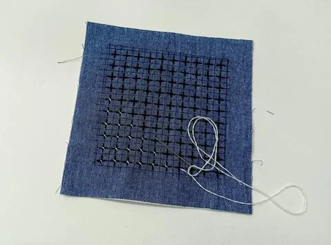 Sashiko embroidery pattern in progress on blue fabric Foto stock