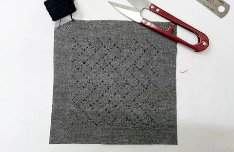 Sashiko embroidery sampler with sewing scissors on a crafting workspace. Stock Photos