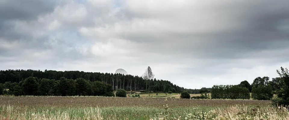 Satellite array visible in rural cloudy countryside field. Foto stock