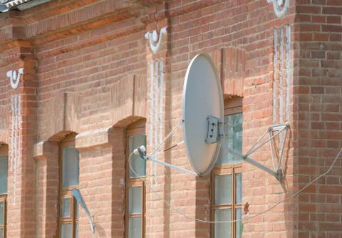Satellite dish on a brick wall. Stock Photos