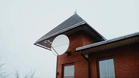 Satellite dish on the facade of a private red brick house with a soft gable roof Stock Footage 218403308