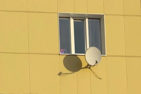 Satellite dish fixed to the wall of a tiled house Stock Photos