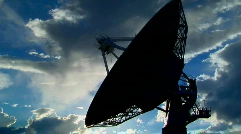 A satellite dish moves in time lapse and is silhouetted Stock Footage