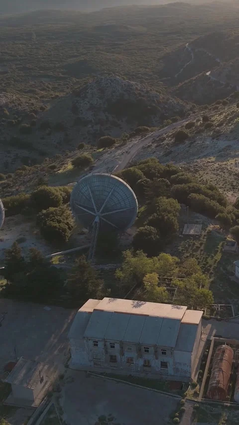 Satellite dishes pointing at setting sun over mountain range Stock Footage 290449873