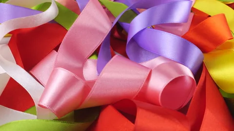 Satin multi-colored ribbons rotate on display case.  库存影片 297427735