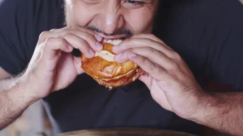 Satisfaction in Every Bite: Close-Up of Man Biting into Burger Video stock 258299387
