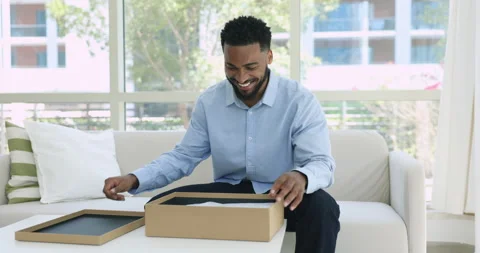 Satisfied African man opens received parcel box with ordered goods Stock Footage 250854997