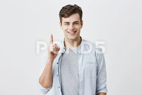 Satisfied and pleased caucasian customer pointing with index finger up at blank Stock Photos
