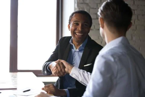 Satisfied black client shaking hands thanking manager for good d 写真素材