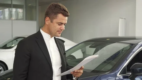 A satisfied buyer reads the documents of the car Stock Footage 80967487