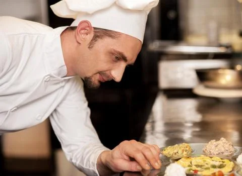Satisfied chef analyzing dish before serving Stock Photos