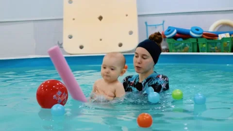 Satisfied child jumping on a float with trainers in the pool Stock Footage 171935294