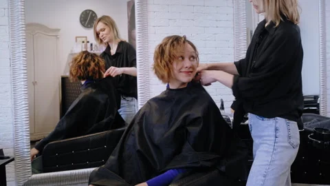 Satisfied Client Checking Haircut in Mirror as Hairdresser Removes Cape Video stock 306273139