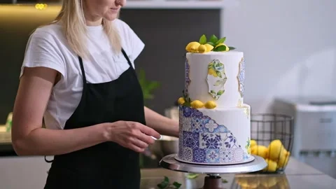 Satisfied confectioner in apron decorating two-tiered cake with patterns and Stock Footage 244667816