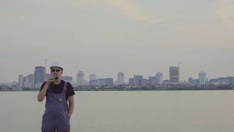 Satisfied Construction worker drinks coffee or tea near the evening city 스톡 동영상 94544660