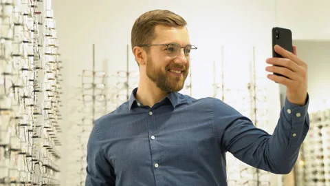 Satisfied customer in new glasses makes a selfie in optic Stock Footage 231679943