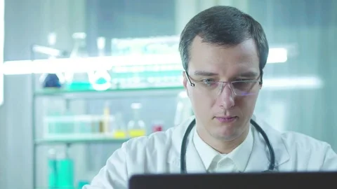 Satisfied doctor working at a computer in the laboratory Stock Footage 82973724