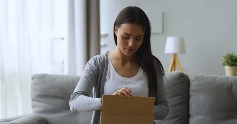 Satisfied female customer open parcel box sit on sofa 스톡 동영상 118265255