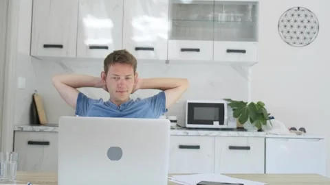 Satisfied handsome man freelancer work on laptop at home puts hands behind head Stock Footage 269995077