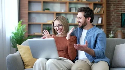 Satisfied happy married couple received great news on laptop while sitting Stock Footage 323809378