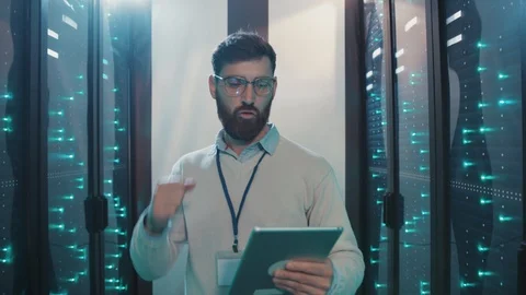Satisfied IT administrator typing on laptop activating server computers on rack Stock Footage 119231919