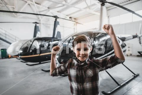 Satisfied kid flourishing arms opposite helicopters indoor Stock Photos