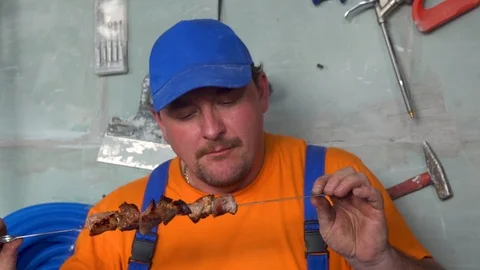 Satisfied male worker eats grilled fried meat with pleasure Stock Footage 115438562