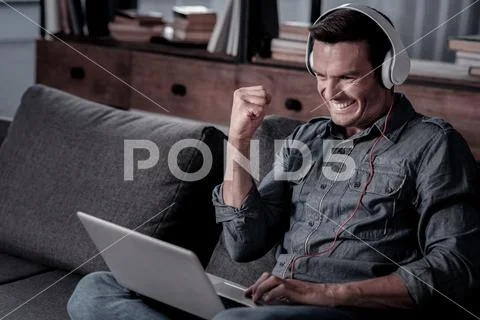 Satisfied man celebrating success while working on laptop Stock Photos